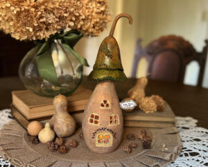 A mushroom house made from natural gourds. The original gourd stem on the top. A "Toad Stool Inn" house sign hangs on the side. 